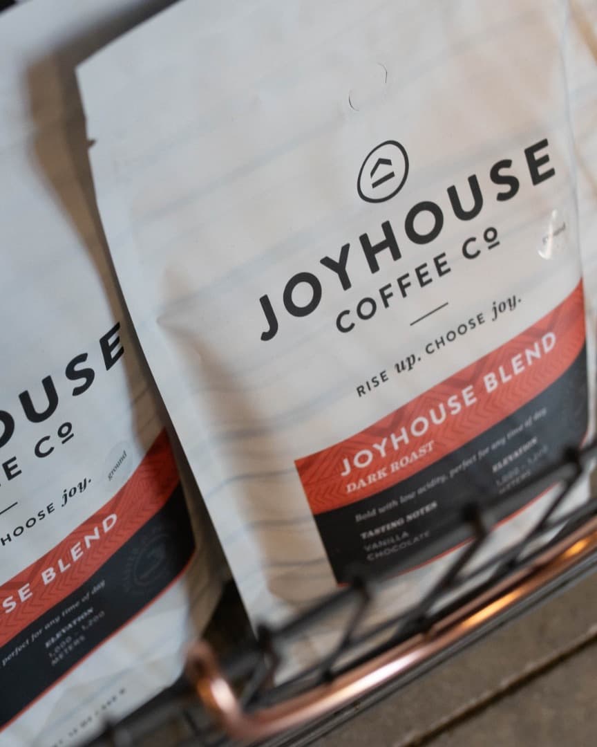 Bags of Joyhouse Blend dark roast in a wire retail basket